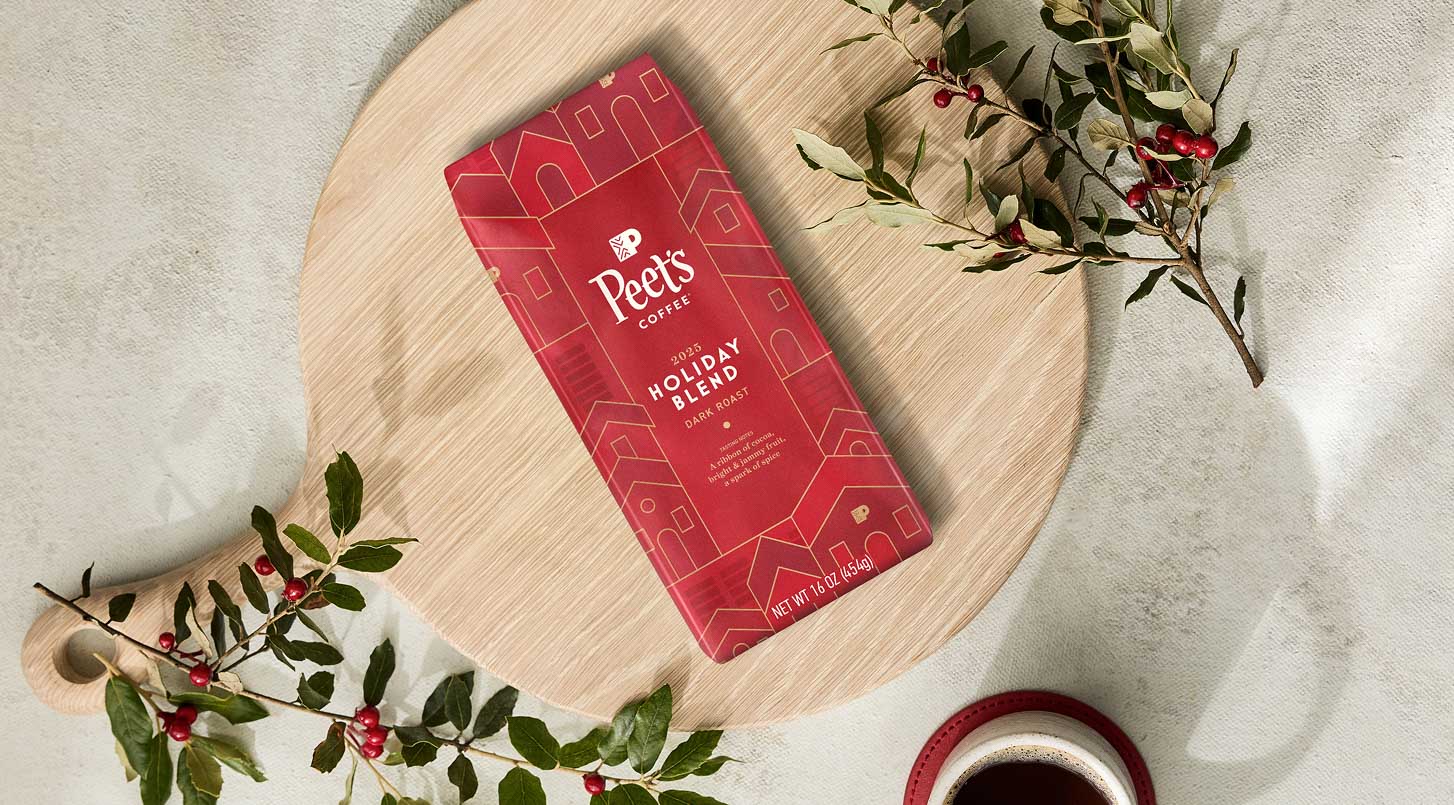 Red coffee package labeled 'Pete's' on a wooden board with holly leaves.